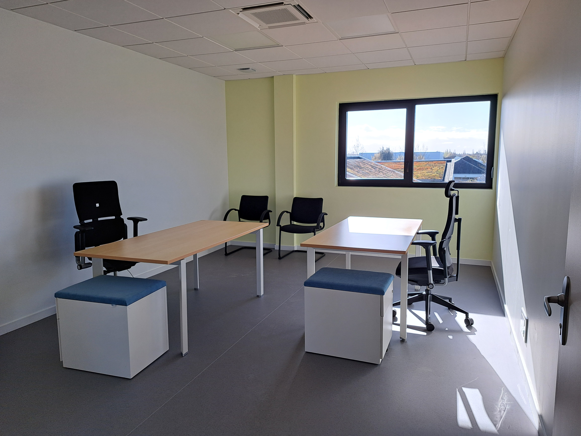 "Bureau équipé de tables, chaises, ottomans et fenêtre."