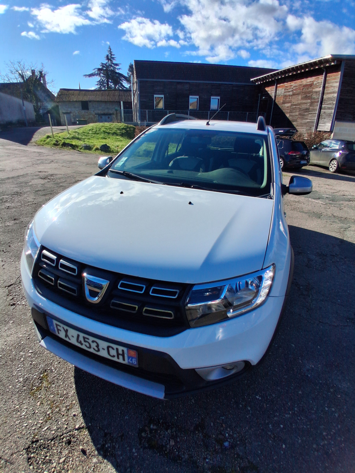 Voiture blanche garée devant un bâtiment.