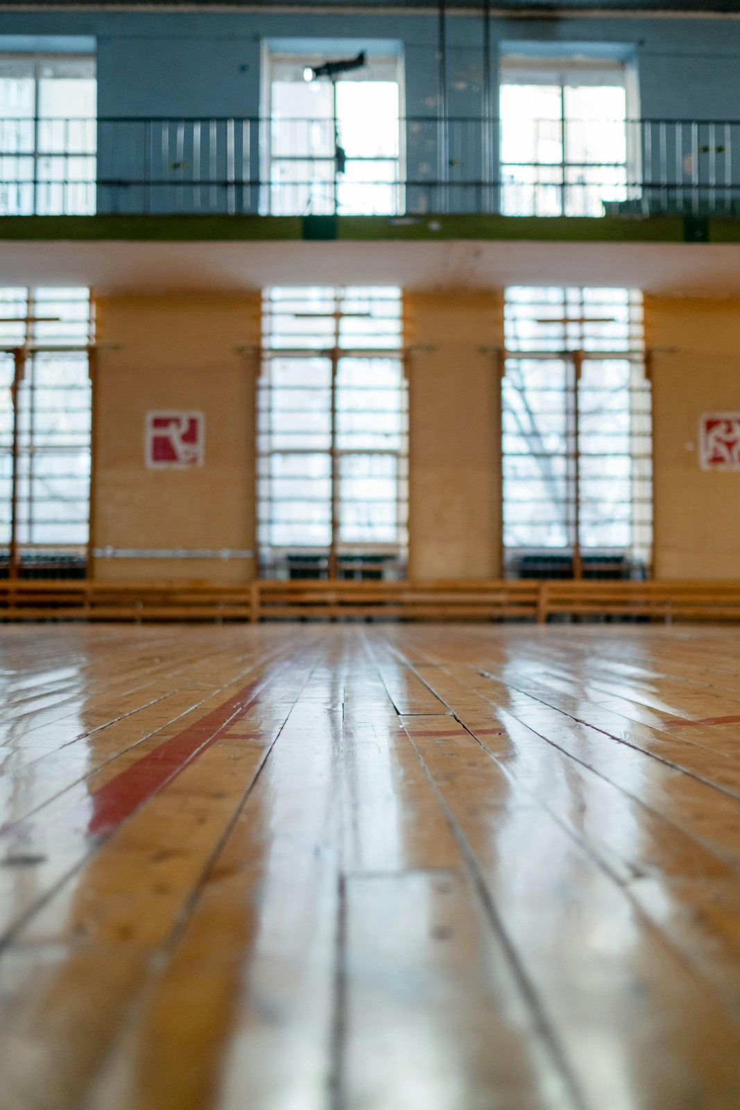 Salle de sport avec parquet, fenêtres et panneaux.