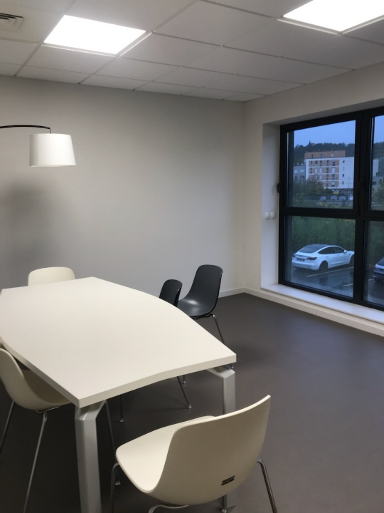 Salle de réunion avec table, chaises, lampe et fenêtre.
