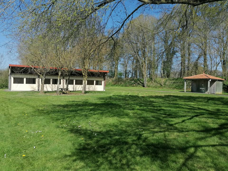 Deux bâtiments avec toits rouges, table de pique-nique, gazebo, pelouse verte, arbres.
