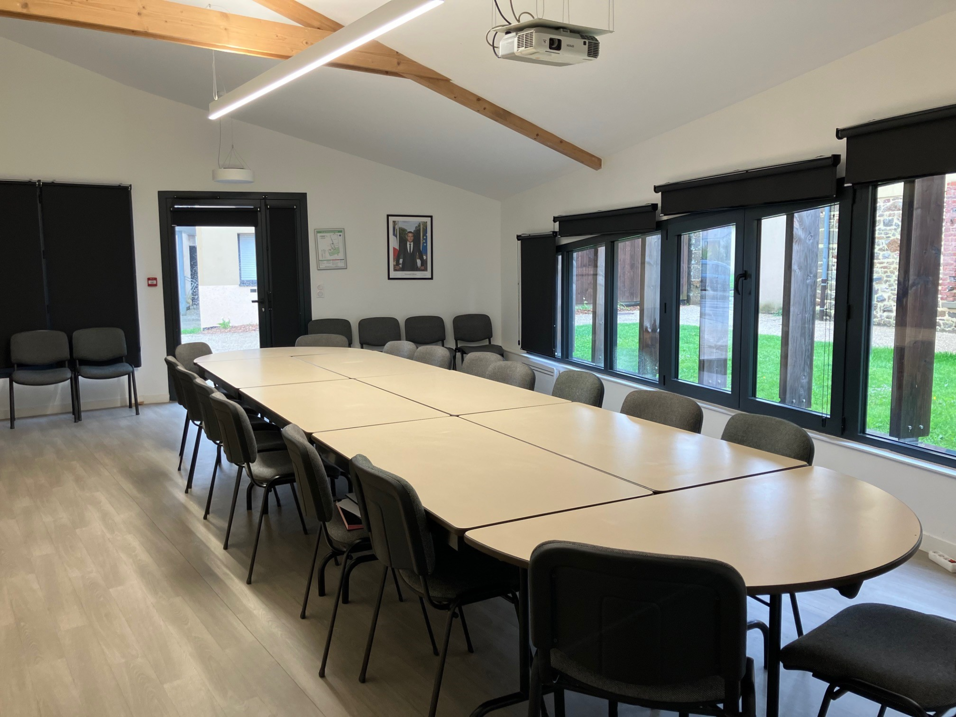 Salle de réunion avec table, chaises, vidéoprojecteur et grandes fenêtres.
