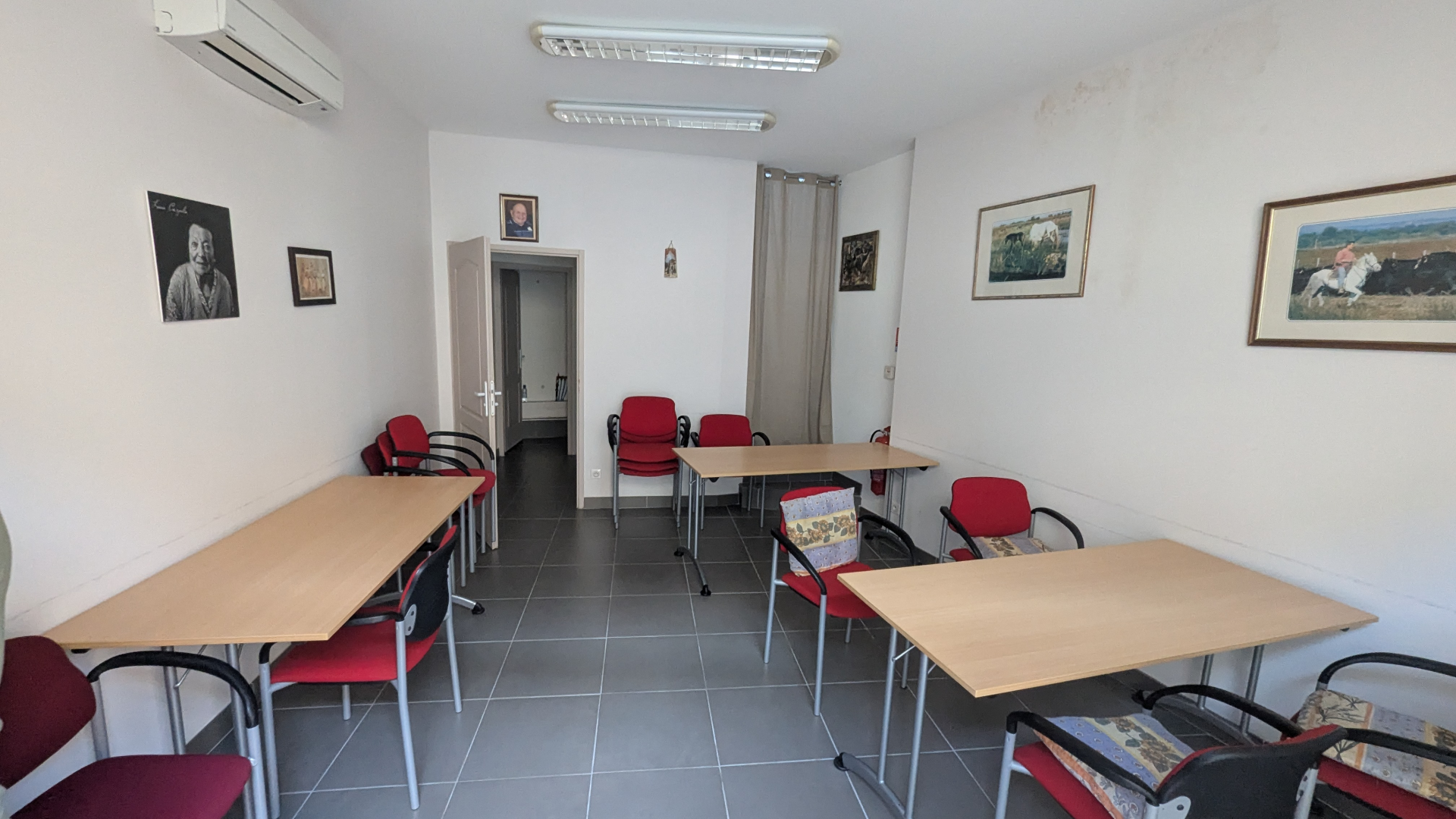 Salle avec tables, chaises, climatiseur, tableaux et lumières.