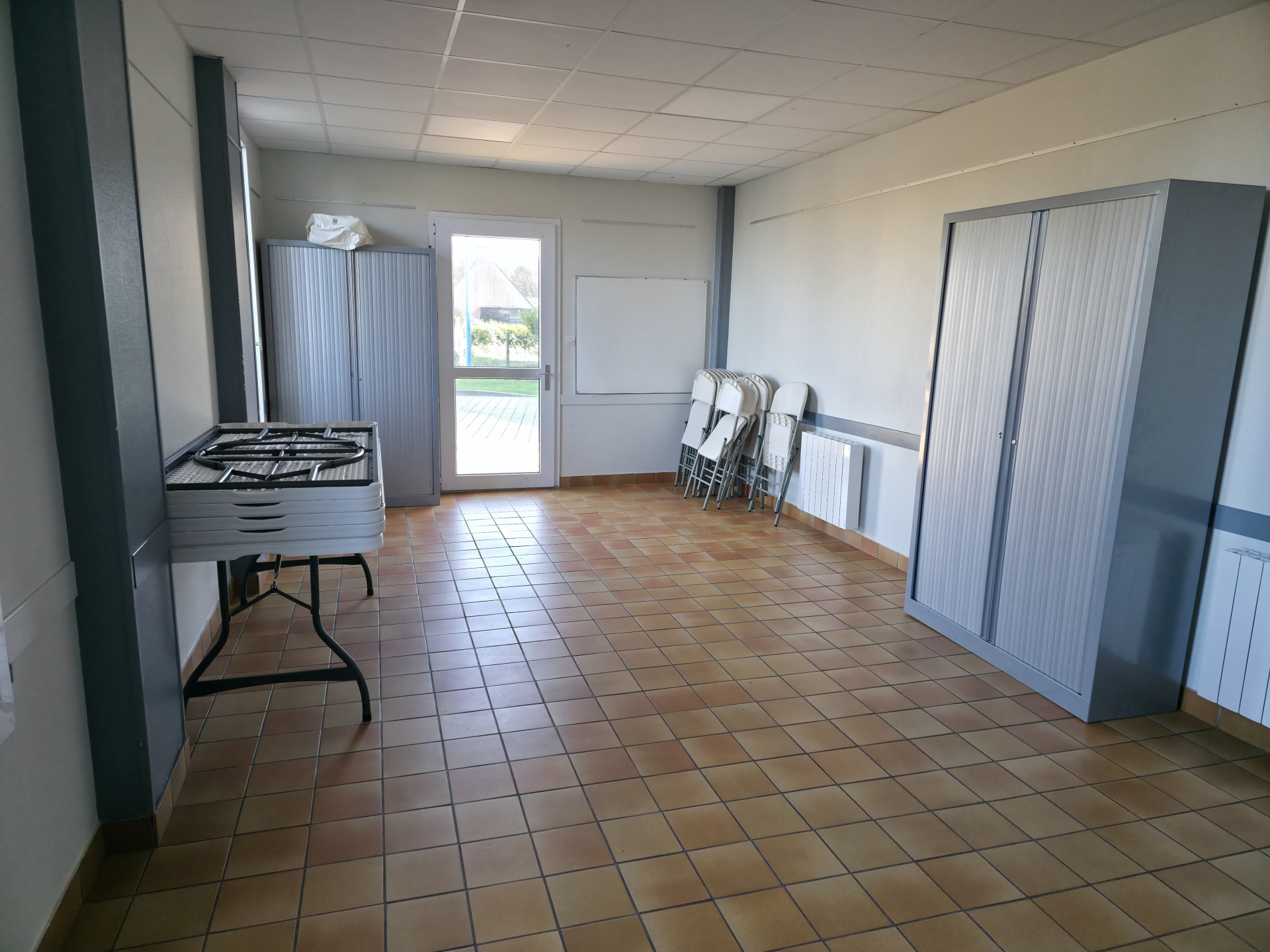 Pièce avec table roulante, porte et classeurs.