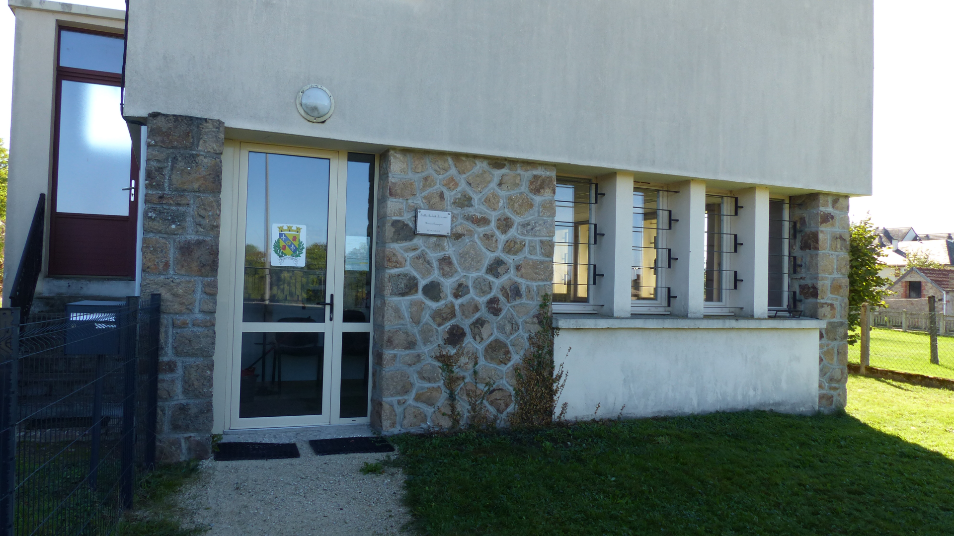 Maison avec porte d'entrée, fenêtres, mur de pierre et pelouse.
