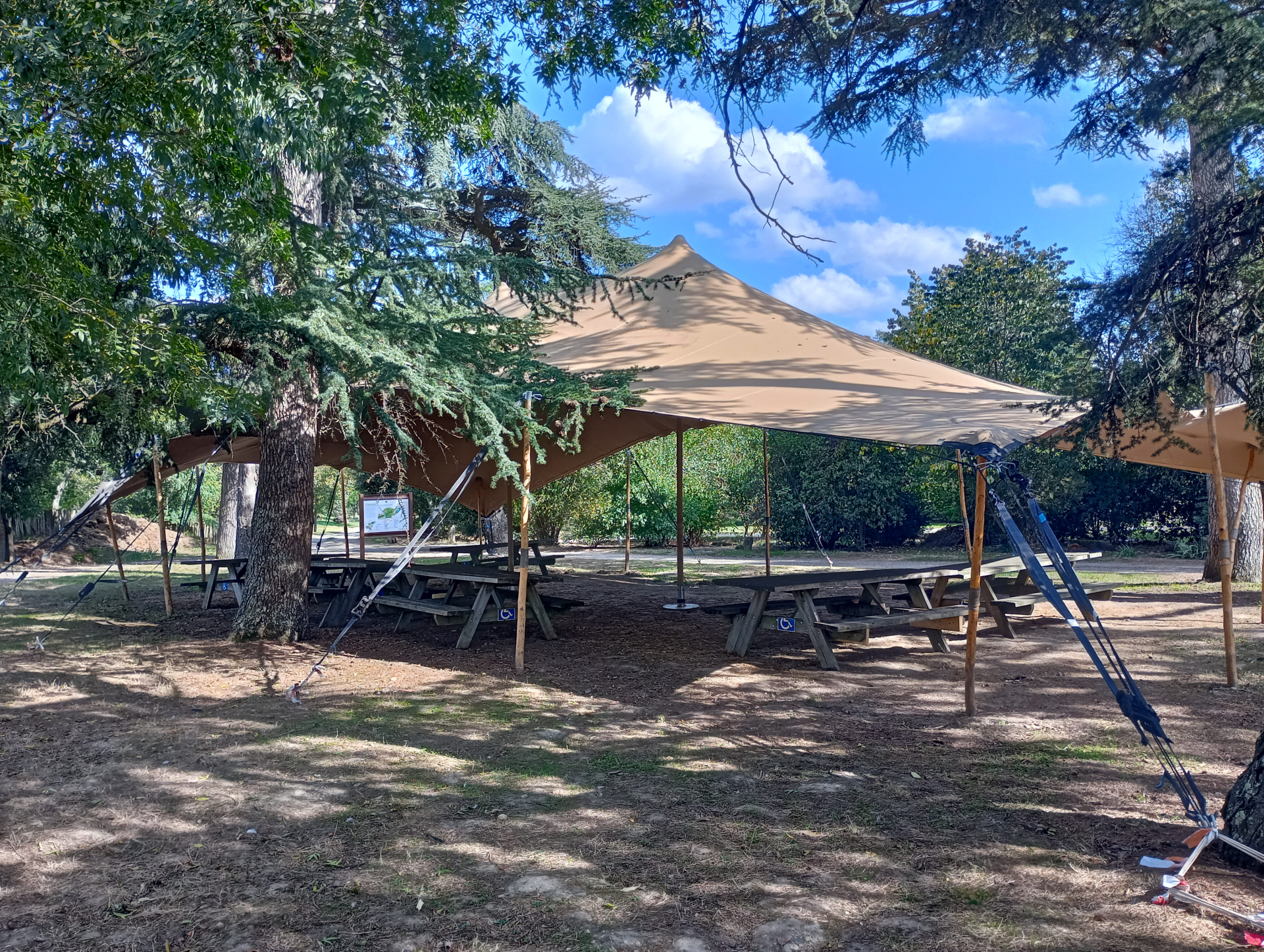 Aire de jeux avec toboggan, balançoire, tables de pique-nique et abris.