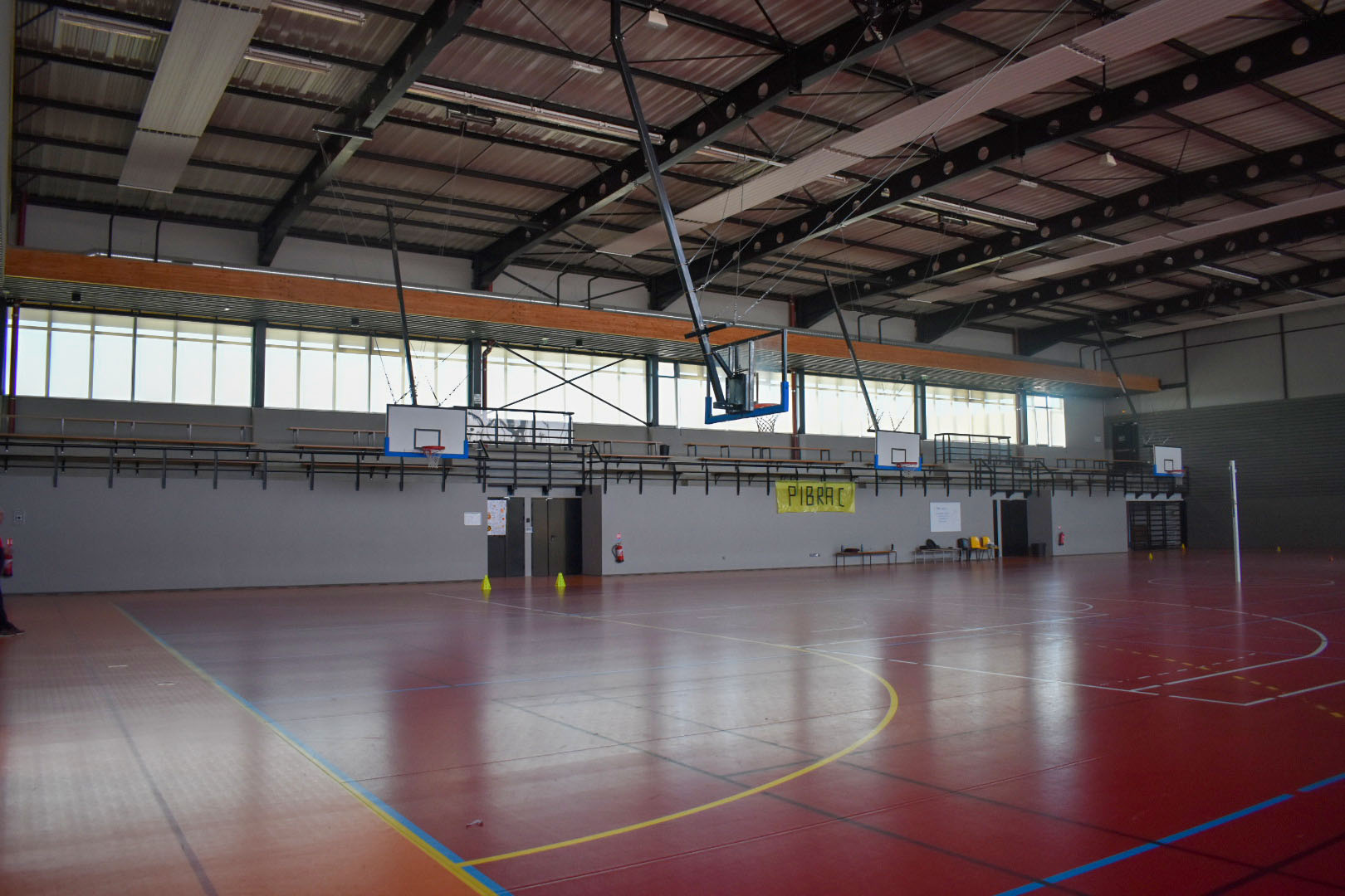 Gymnase avec panier de basket, panneaux de score, et lignes de terrain.