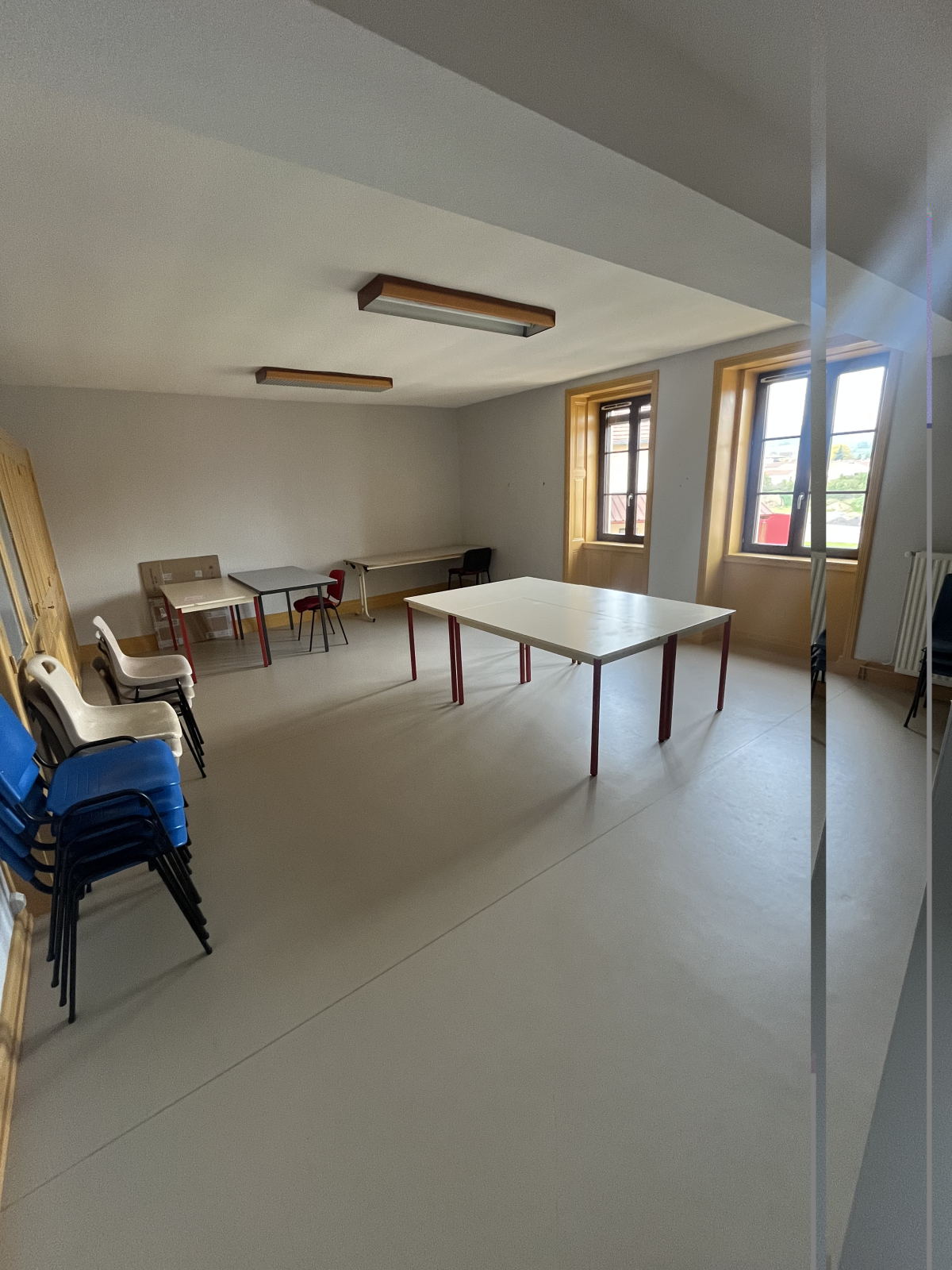 Salle avec tables, chaises, fenêtres et lumières.