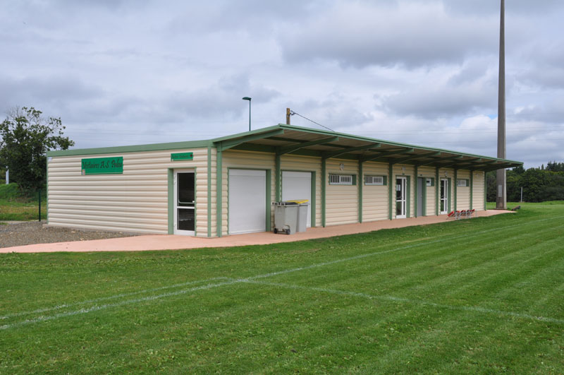 Bâtiment avec portes, fenêtres et climatiseur extérieur sur terrain gazonné.