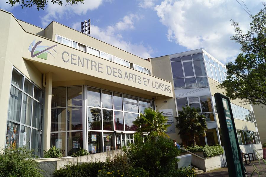 Bâtiment avec enseigne "Centre des Arts et Loisirs", grandes fenêtres, plantes et arbre.