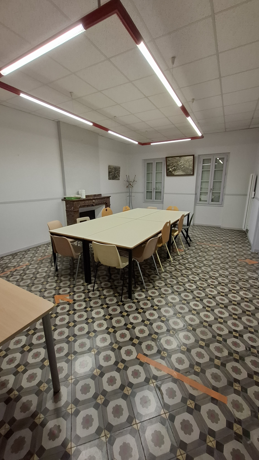 Salle avec table, chaises, meuble et éclairage.