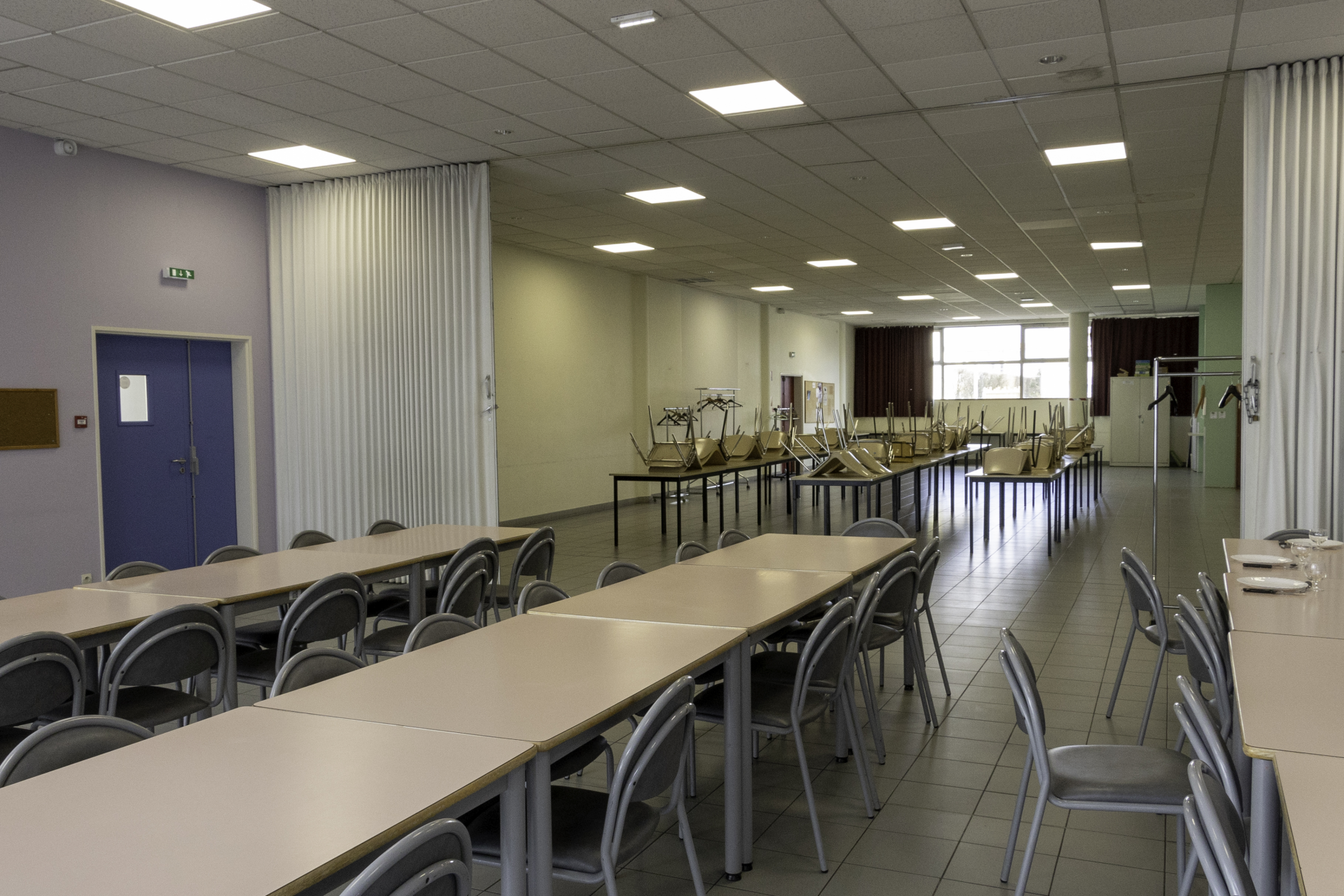 "Salle avec tables, chaises, vélo d'appartement, rameur et miroir en fond."