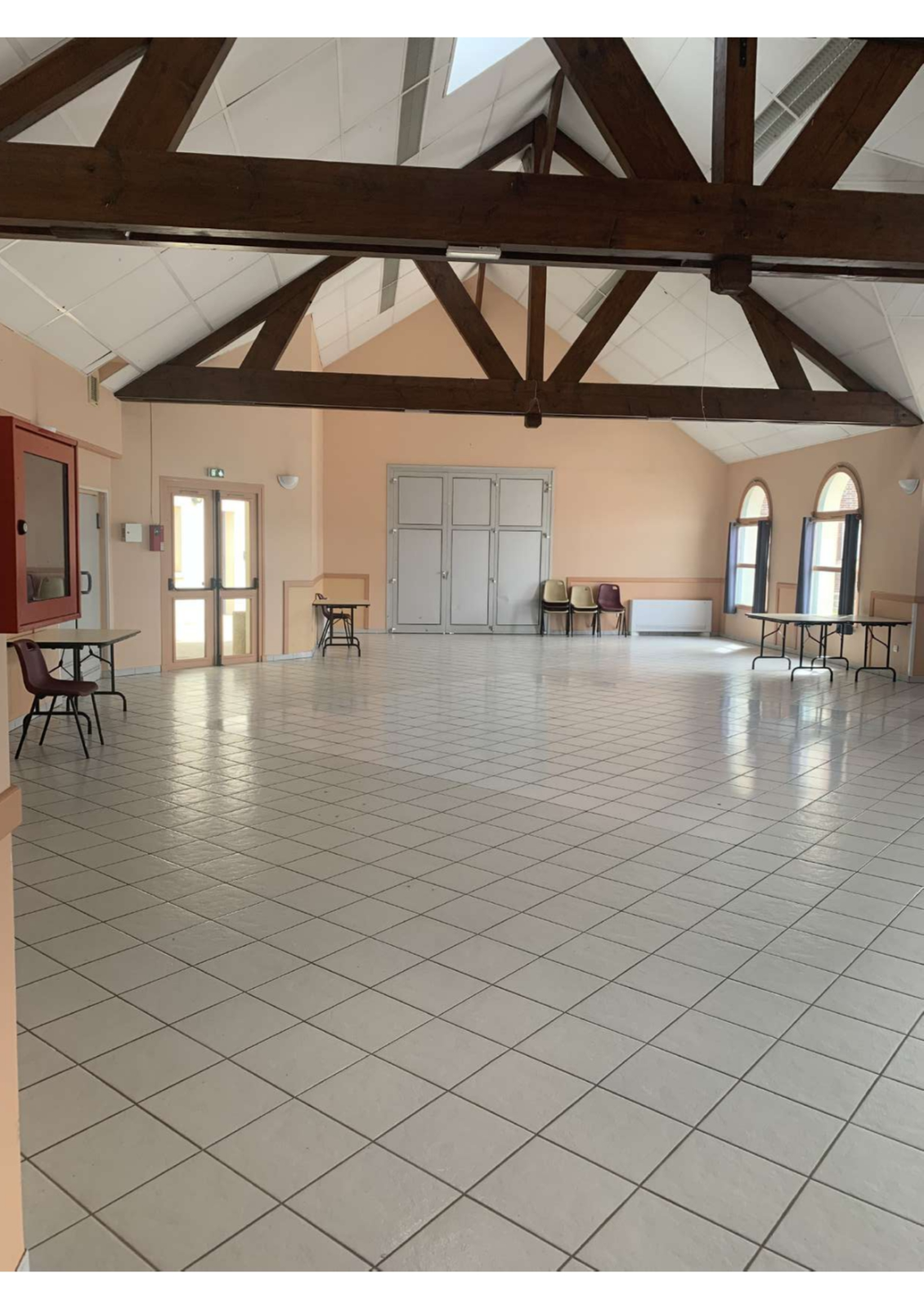 Salle avec tables, chaises, et portes.