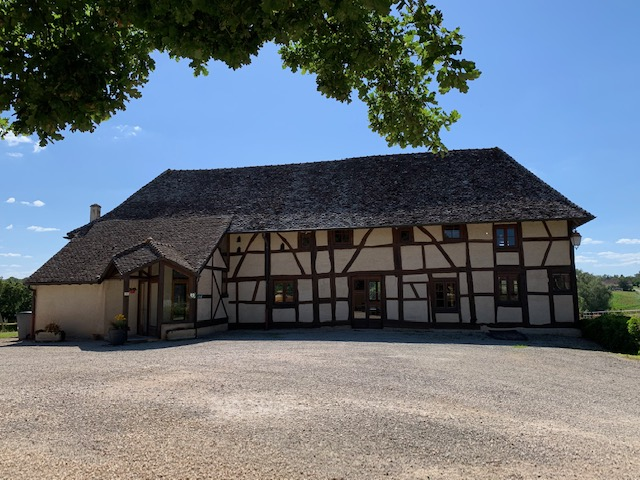 Maison à colombages, toit en chaume, entrée, fenêtres, arbre, ciel.