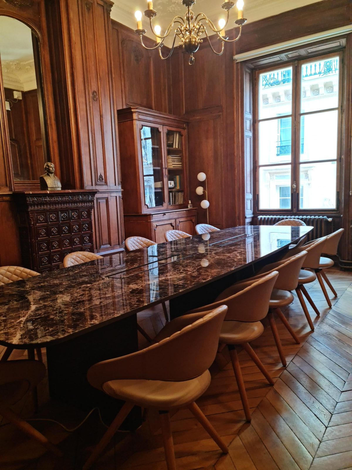 Salle à manger avec table en marbre, chaises, buffet et lustre.