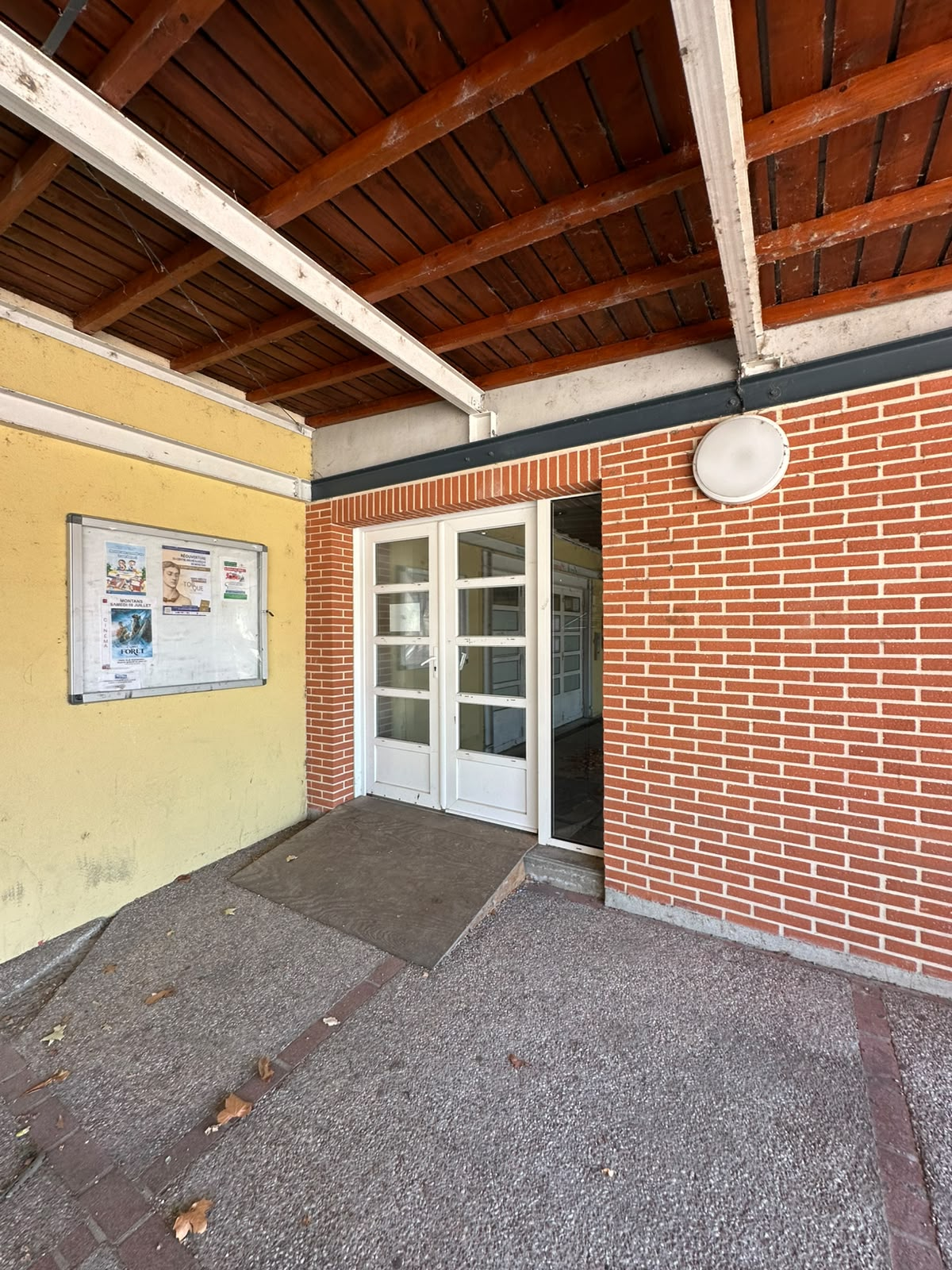 Entrée avec porte, rampe et affiche.