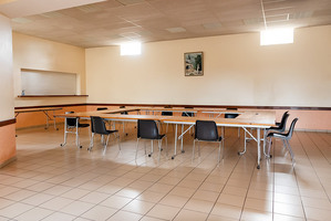 Salle avec tables, chaises, plan de travail et cadre au mur.