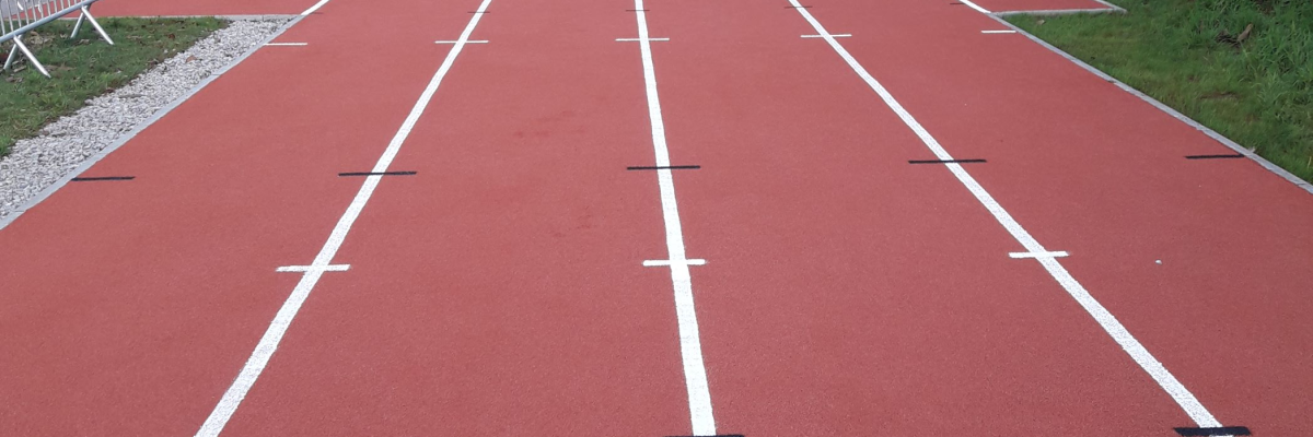 Piste d'athlétisme rouge avec lignes blanches.