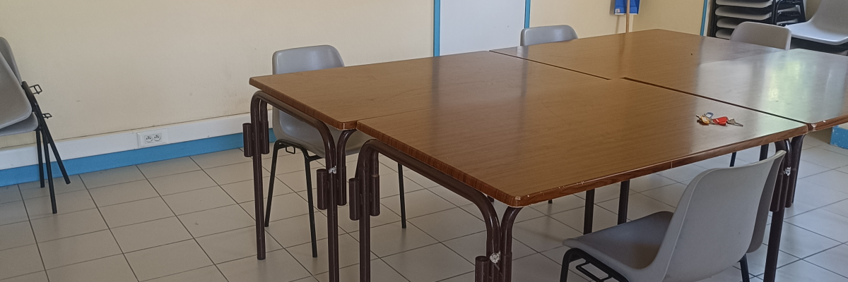 Pièce avec table, chaises, balai et porte ouverte.