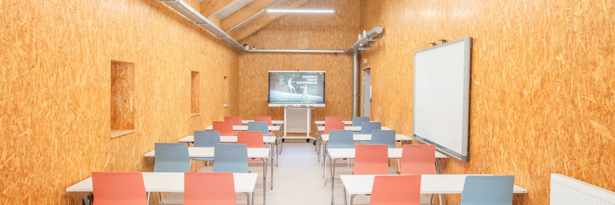 "Salle de classe avec tables, chaises,projecteur, écran et tableau blanc."