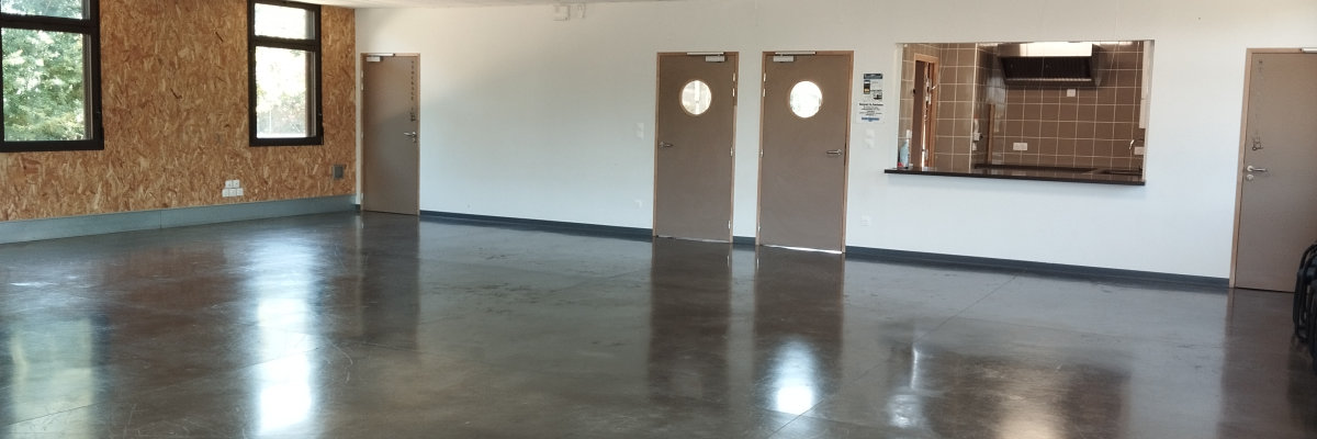 Salle vide avec sol en vinyle, murs blancs, portes, fenêtre, miroir et éclairage au plafond.