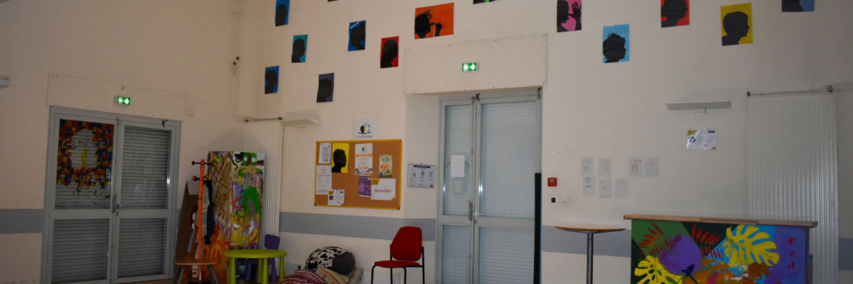 Salle avec tableaux, porte, tableau d'affichage, chaises, et table.