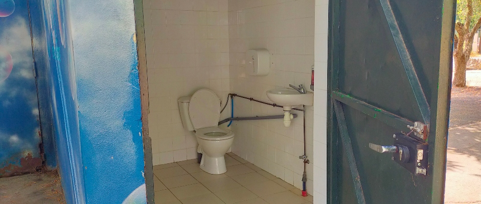 Cabine de toilettes avec WC, lavabo, porte et serrure.