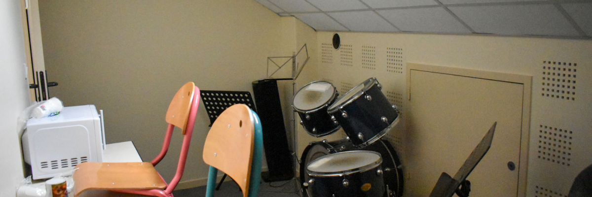 Pièces avec batterie, microwaves, table, microphones et chaises.