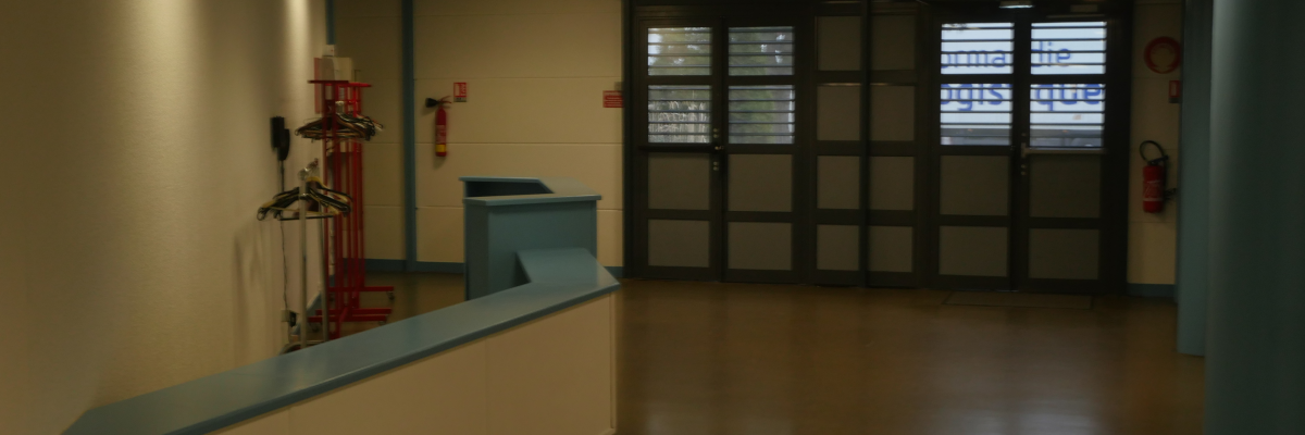 Couloir avec comptoir, extincteurs, porte-manteau et portes vitrées.