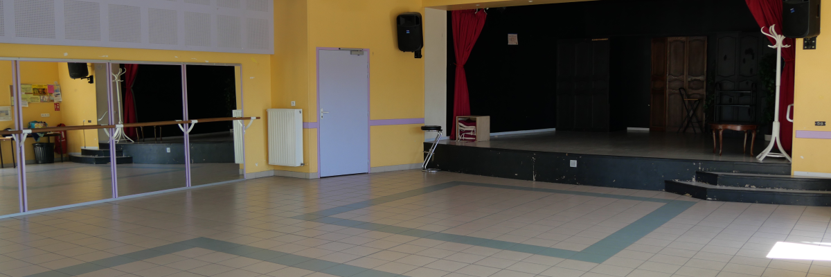 Salle avec barre de danse, scène, rideau, porte et miroir.