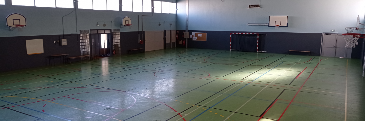 Salle de sport avec paniers de basket, terrains de jeu, bancs et portes.
