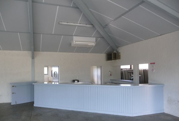 Comptoir avec plaque de cuisson, four, hotte et miroir.