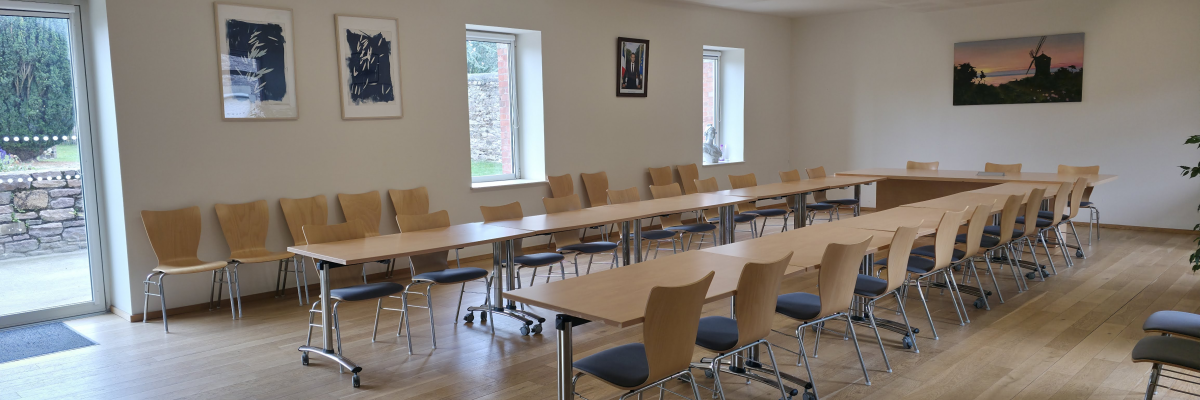 Salle de réunion avec tables, chaises et tableau blanc.