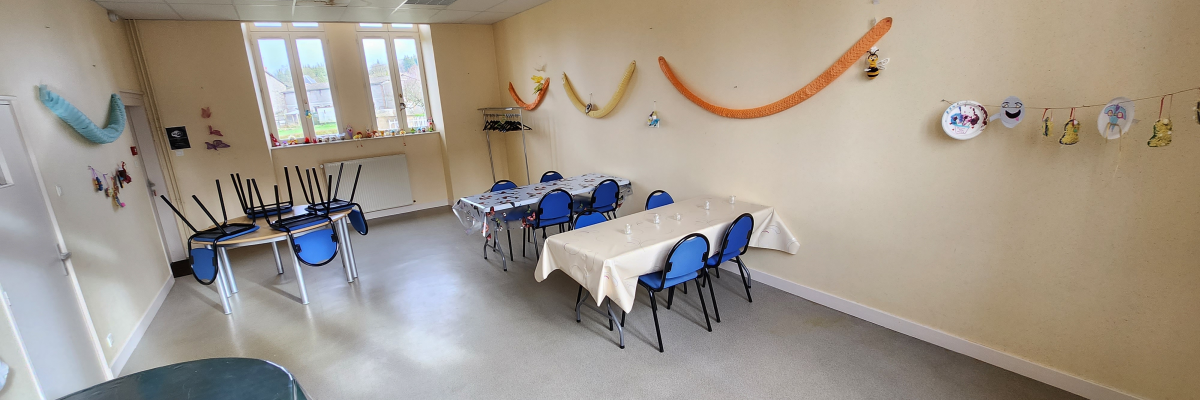 Salle avec tables, chaises, décoration murale, fenêtres et rideaux.