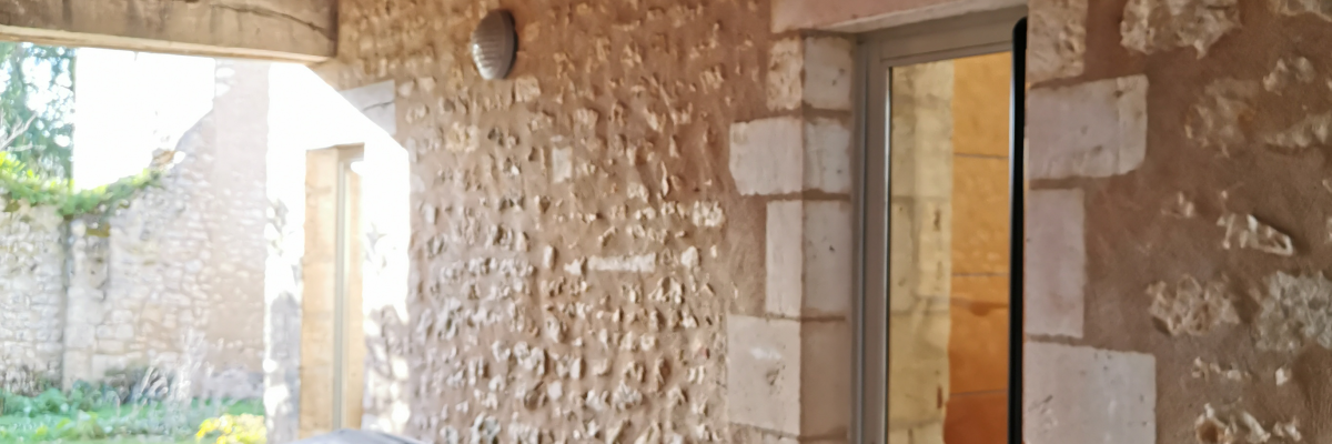 Banc sous un porche en pierre, vue sur jardin.