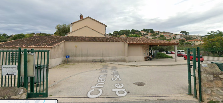 Bâtiment avec entrée, voiture et paysage.