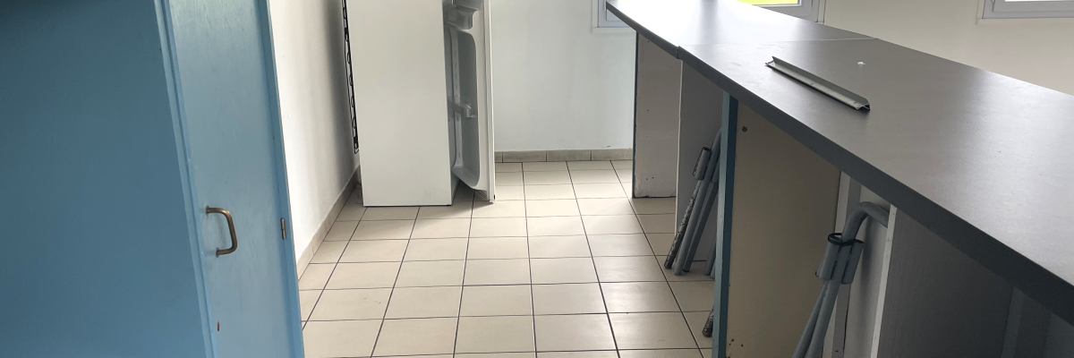 Cuisine avec plan de travail, évier, lave-linge et porte bleue.