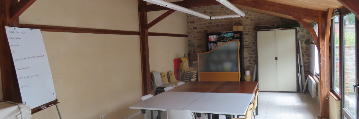 Salle avec table, chaises, tableau blanc, écran, paperboard et étagères.