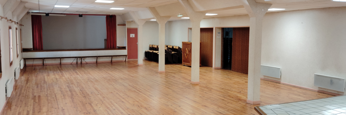 Salle spacieuse avec parquet, tables, chaises, rideaux, et portes.