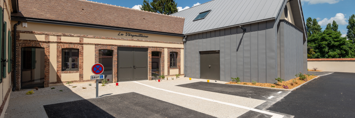 Bâtiment avec parking, places handicapées et interdictions de tourner.