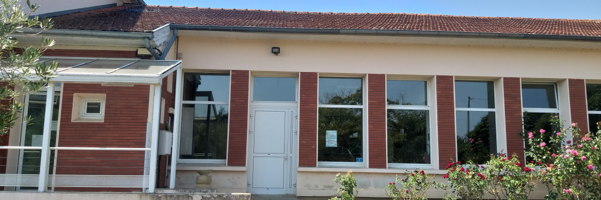 Bâtiment avec toit en tuiles, murs rouges et blancs, fenêtres, porte, auvent et fleurs.