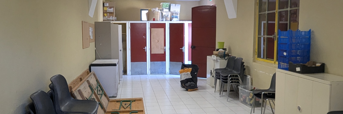 Salle d'attente avec chaises, tables, distributeur d'eau et armoire.