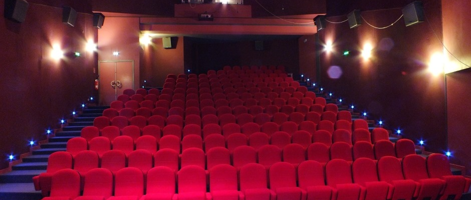 Salle de cinéma avec sièges, projecteur, éclairage et scène.