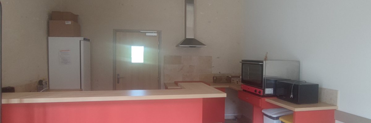 "Cuisine avec îlot, table, micro-ondes, télévision et hottes."