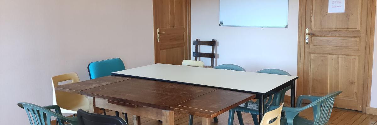 Salle avec table, chaises, tableau blanc et portes en bois.