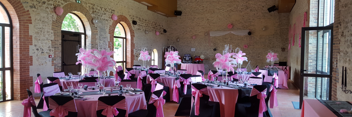 Salle avec tables, chaises, nappes, verres, et décorations florales.
