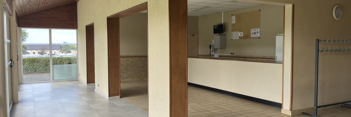 Salle avec sol carrelé, comptoir, étagères, horloge murale et porte vitrée.