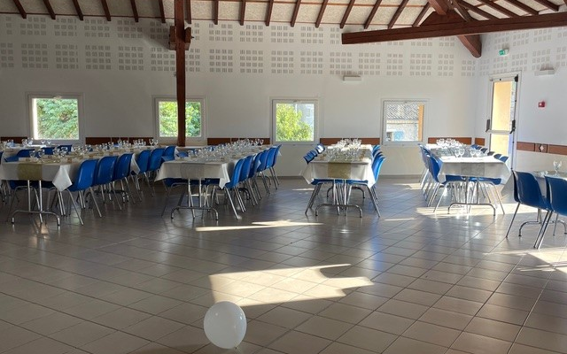Salle avec tables, chaises, nappes blanches et ballon blanc.
