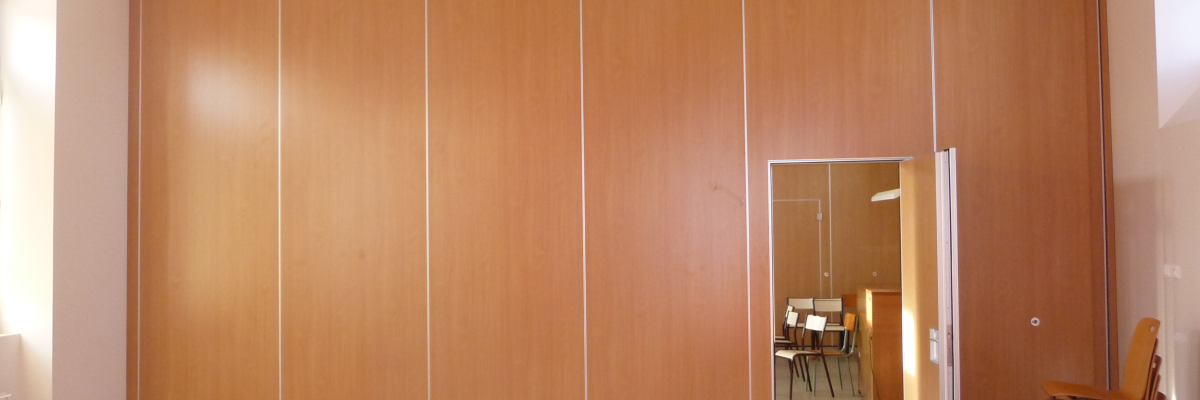 Salle avec portes en bois, table, chaises, ouvertures vers une autre pièce.