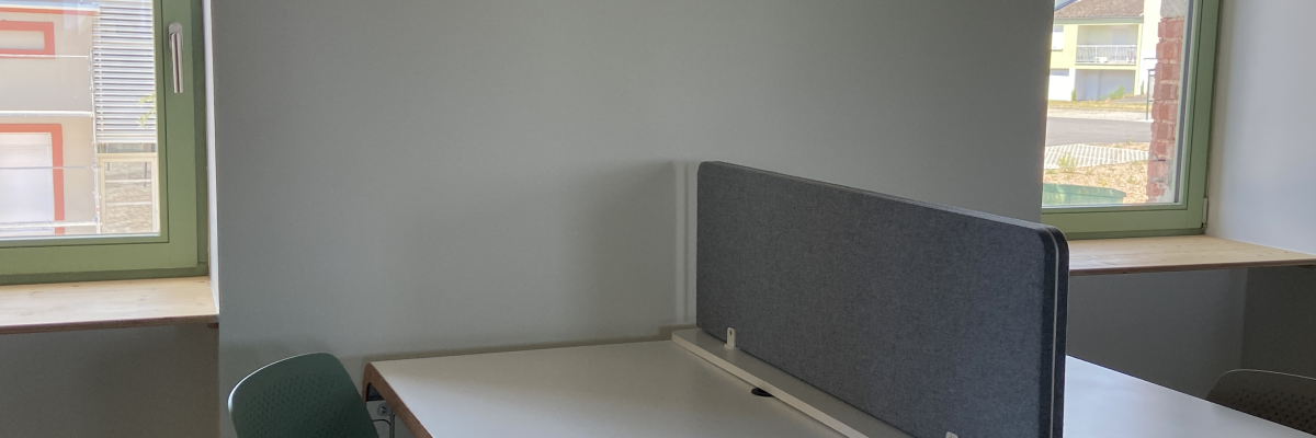 Bureau avec séparation, chaise, tabouret et fenêtres.